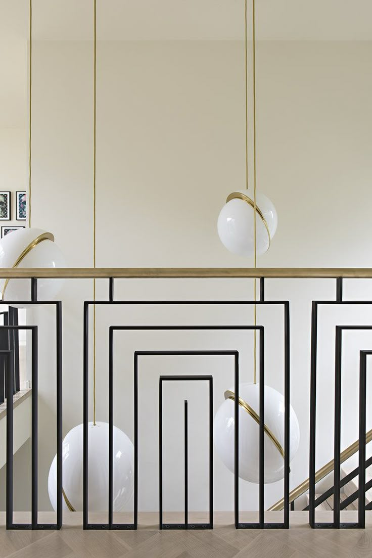 a room with white walls, black and gold railings and pictures on the wall