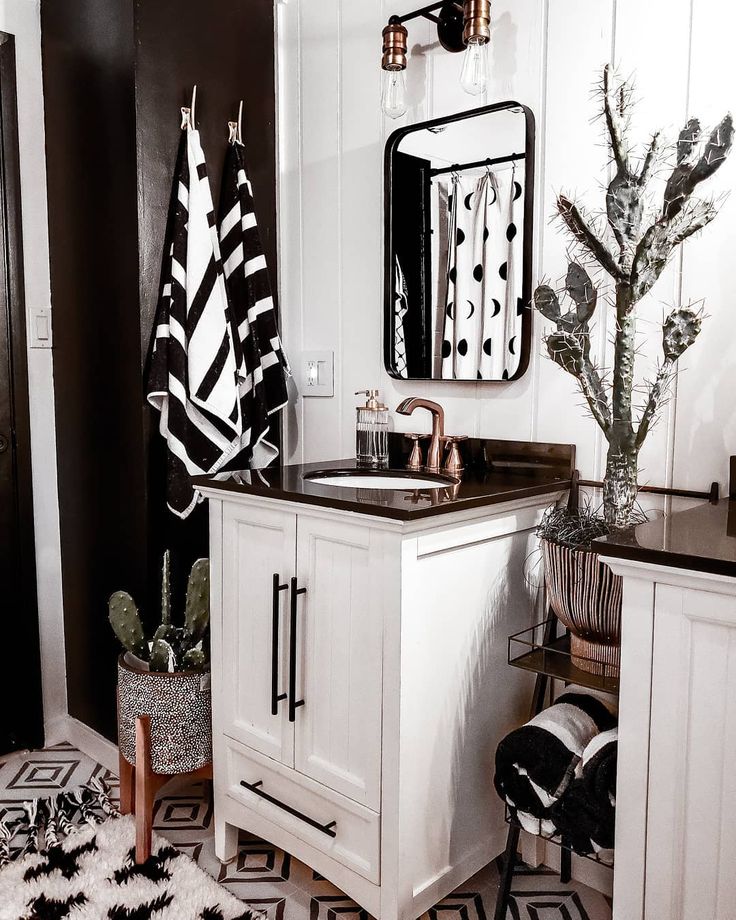 a white bathroom with black and white decor on the vanity, rugs and mirror