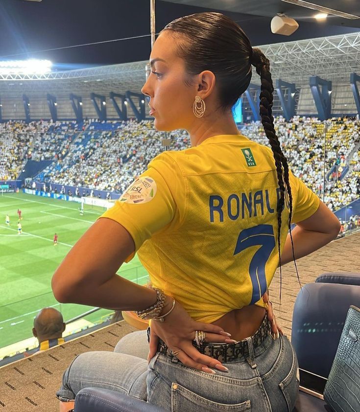 a woman sitting in a stadium with her back to the camera and listening to music