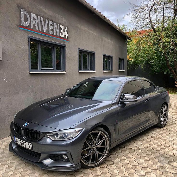 a grey bmw car parked in front of a driveen134 building with the words driveen134 on it's side