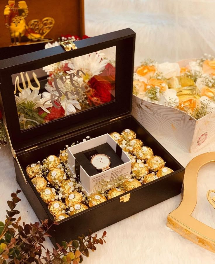 a box filled with gold and white candy next to other boxes full of candies