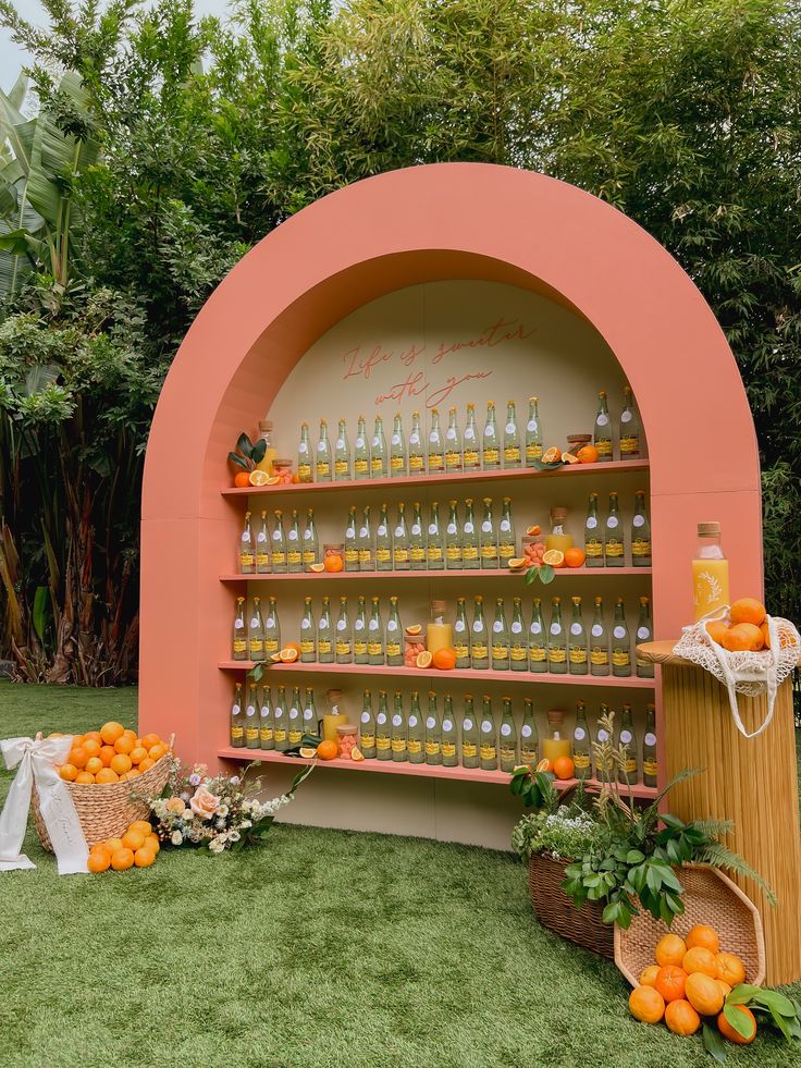 an outdoor display with oranges and bottles on the shelves, along with other decorations