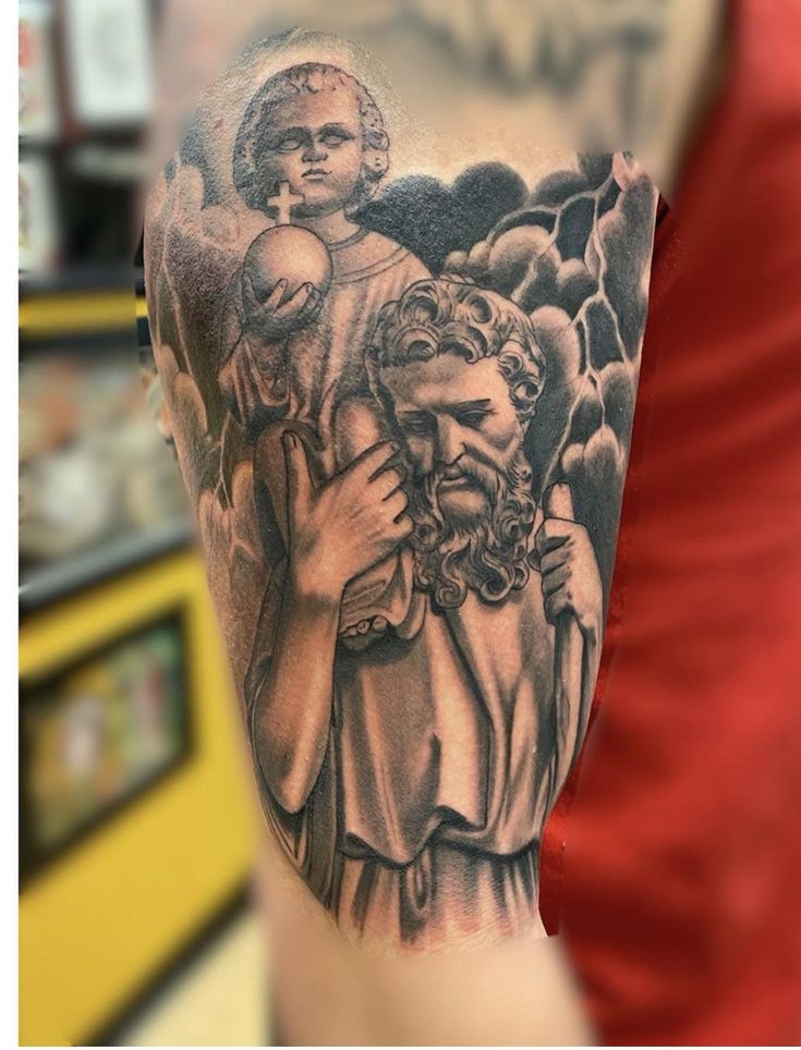 a man with a tattoo on his arm holding a child and an angel above him