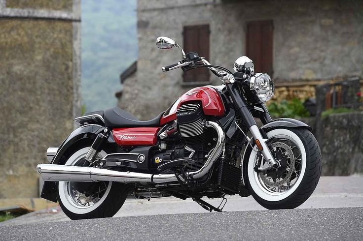 a red and black motorcycle parked in front of an old building on the side of a road