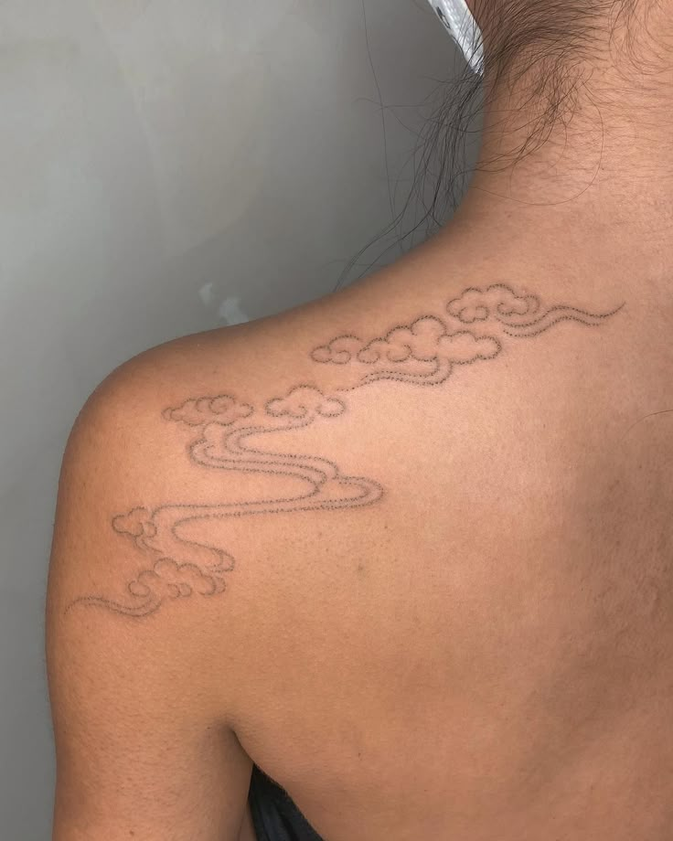 the back of a man's neck with clouds and stars tattoo on his left shoulder