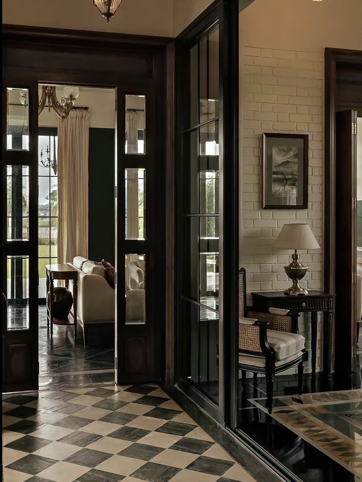 a living room with black and white checkerboard flooring, chandelier and two chairs