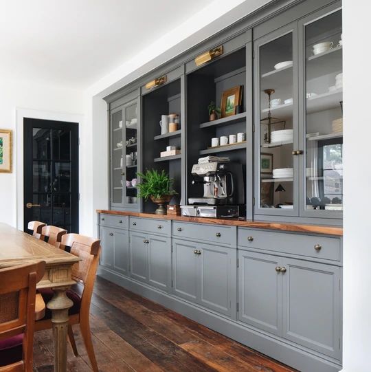 a kitchen with gray cabinets and wooden table in front of the counter top, along with an area rug on the floor