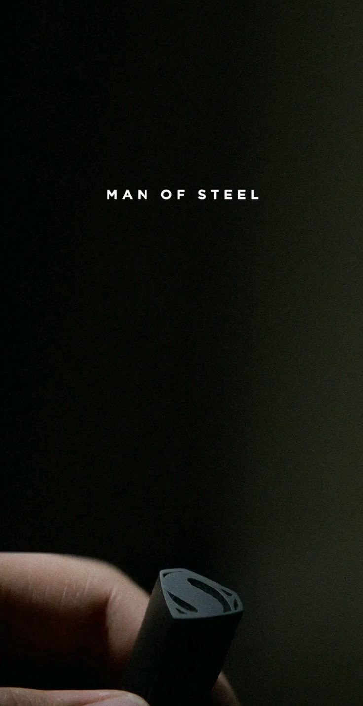 a person holding a remote control in their hand with the words man of steel on it