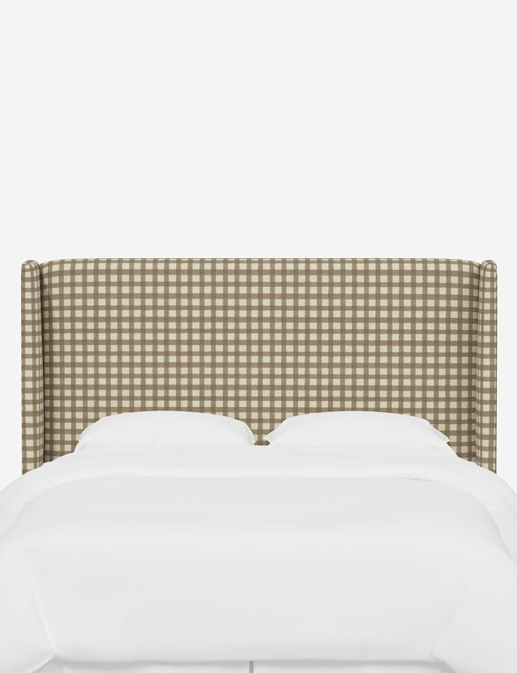 an upholstered headboard with checkered fabric and white sheets on the bed