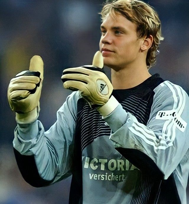 a young man holding a cell phone in his right hand while standing on a soccer field