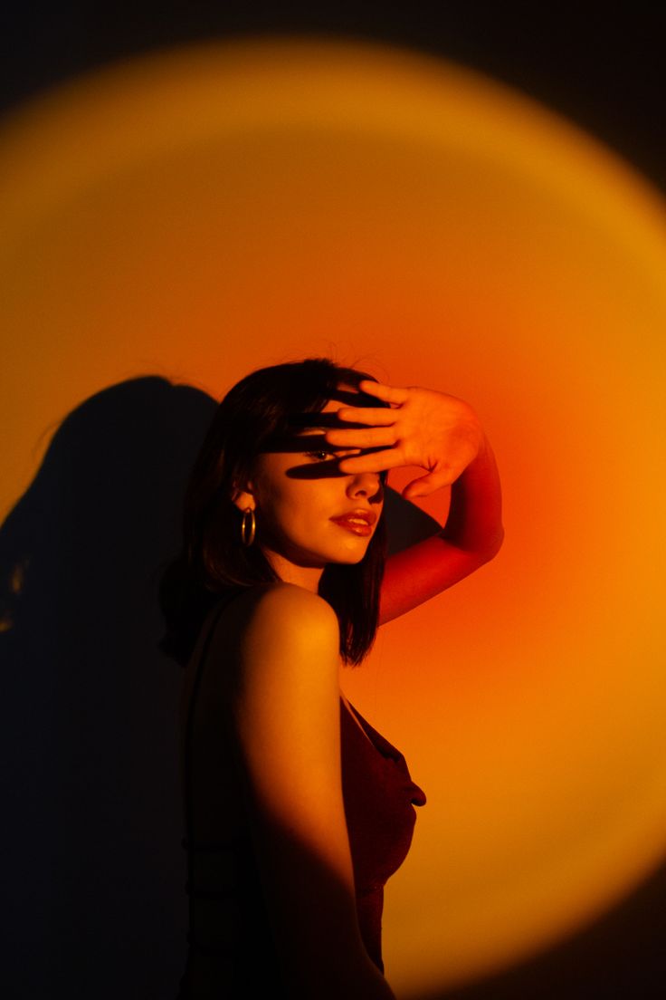 a woman with her hand on her head in front of an orange and yellow background