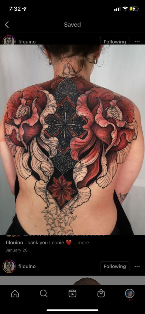 the back of a woman's body with flowers on it and an intricate cross tattoo