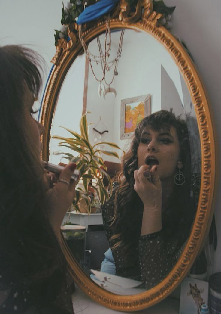 a woman is brushing her teeth in front of a mirror and looking into the mirror