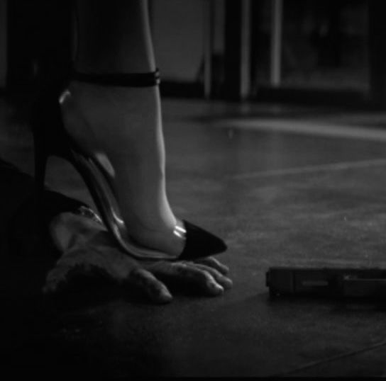 black and white photograph of woman's feet with cell phone on the ground next to her