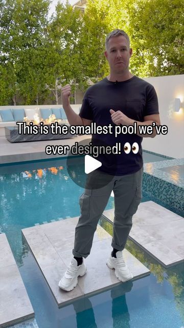 a man is standing on the edge of a swimming pool with his hands in his pockets