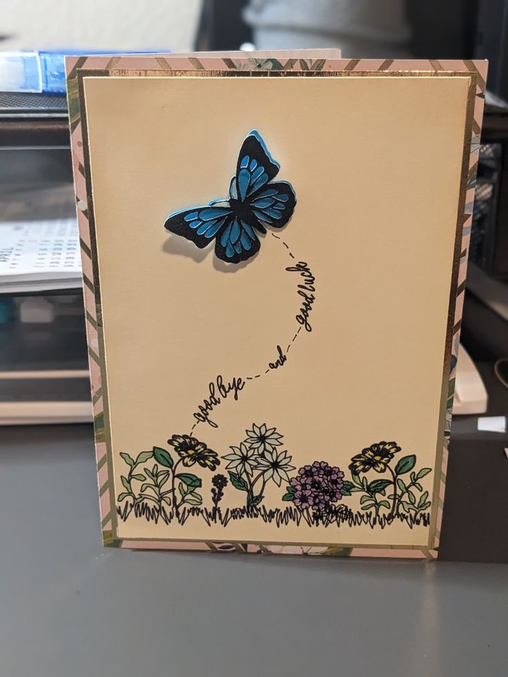 a card with a butterfly on it sitting on top of a table next to a computer