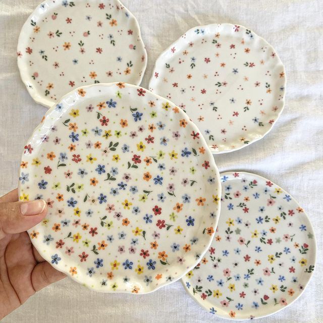 hand holding four plates with colorful flowers on them