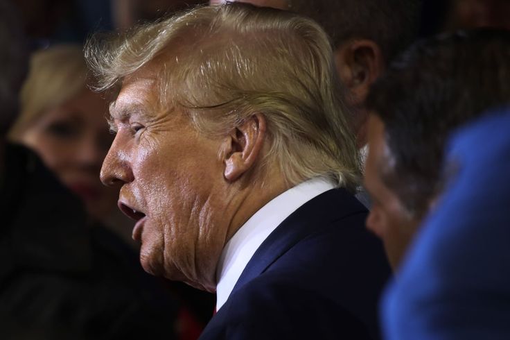 a close up of a person wearing a suit and tie with other people in the background