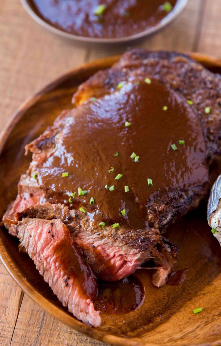 a wooden plate topped with meat covered in gravy