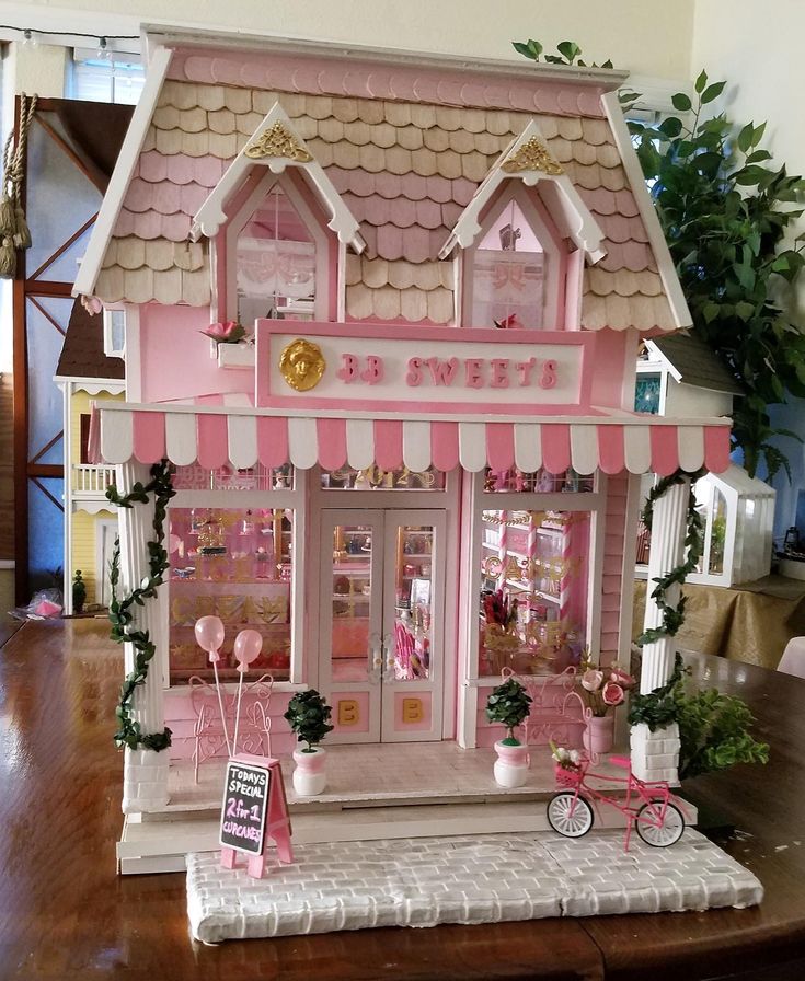 a pink and white doll house with lots of decorations on the front door, windows, and porch