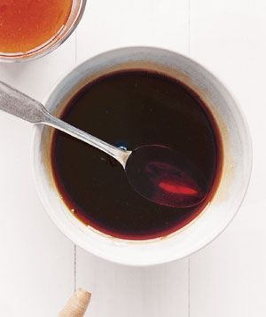 two bowls filled with liquid and spoons on top of a white wooden table next to each other