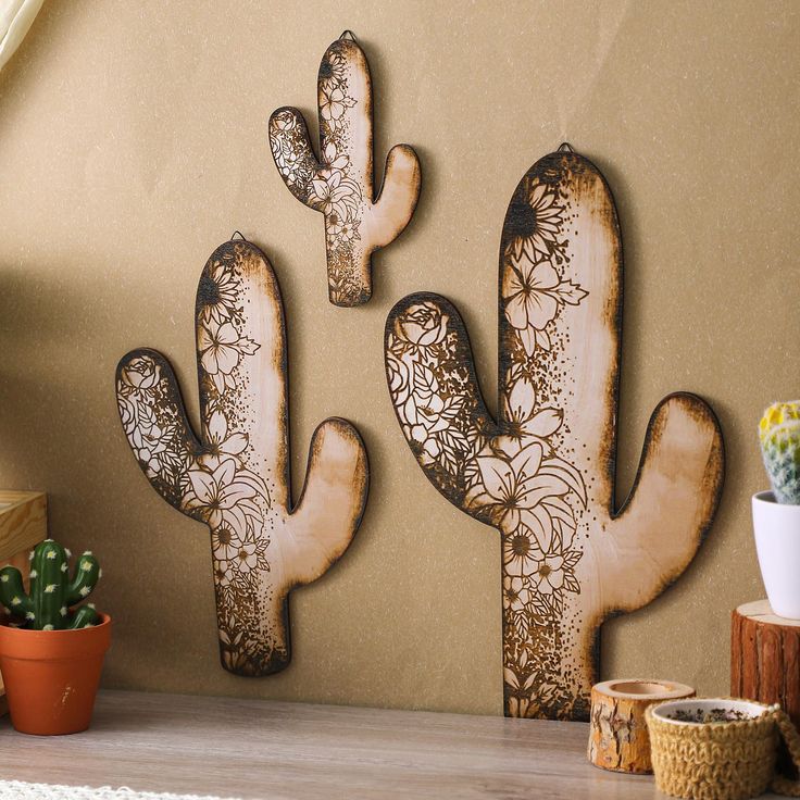 three wooden cactus wall hangings on a wall next to a potted cacti