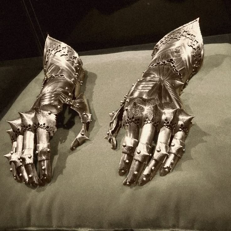 two metal gloves sitting on top of a pillow