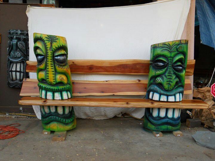 three carved wooden masks sitting on top of a bench next to a white sheet covered wall