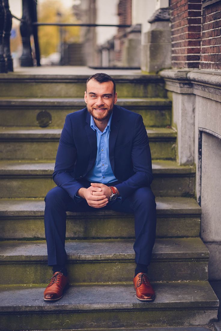 a man in a suit sitting on some steps with his arms crossed and looking at the camera