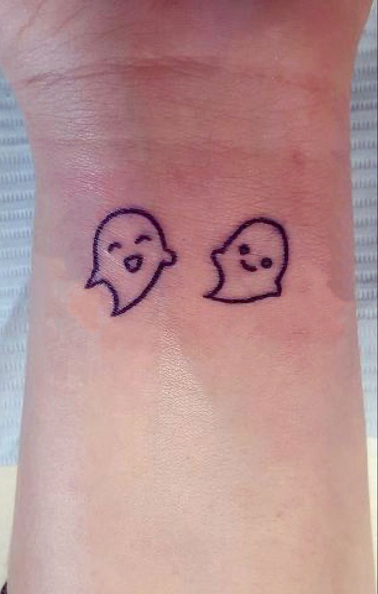 a wrist tattoo with two faces drawn on it