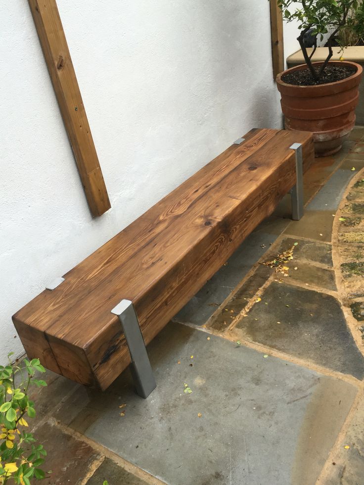 a wooden bench sitting next to a potted plant