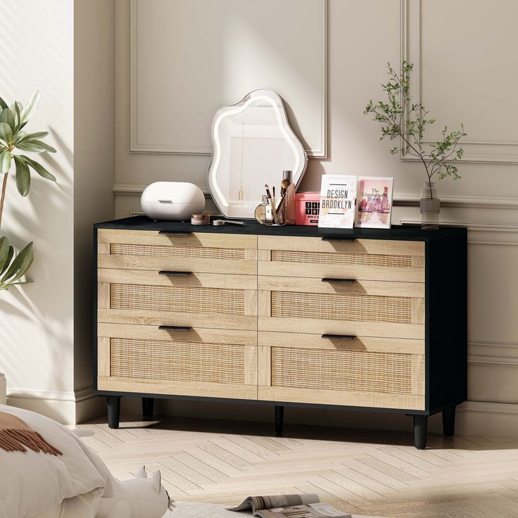 a dresser with many drawers and pictures on it in a room next to a potted plant