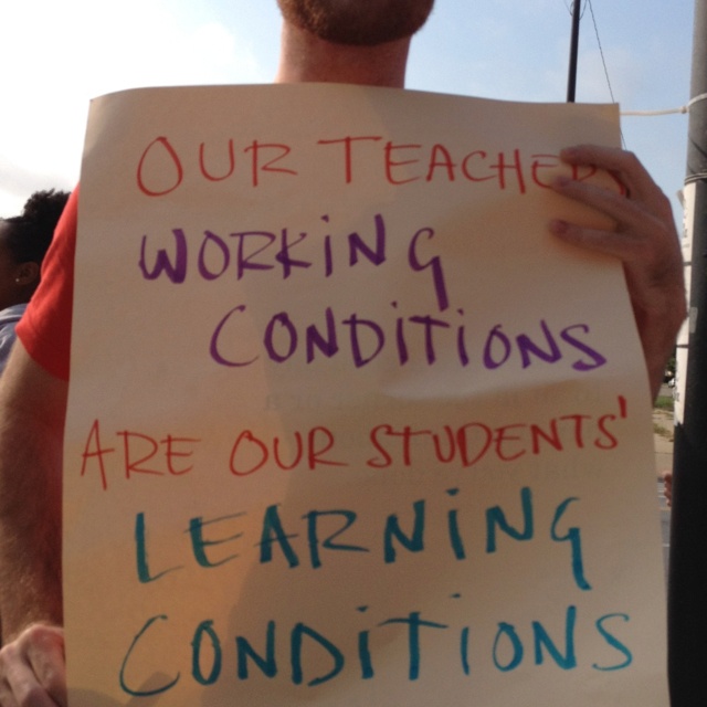 a man holding a sign that says our teacher working conditions are our students learning conditions