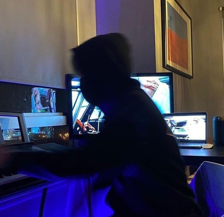 a person sitting at a desk in front of two monitors