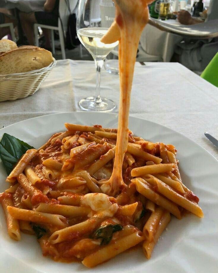 a plate of pasta with sauce being drizzled over it on a table