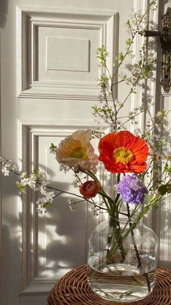 a vase filled with flowers sitting on top of a wicker table next to a door