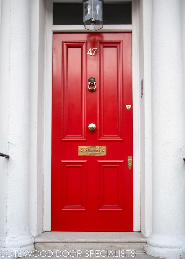 a red front door with two white pillars and a lamp on the side of it