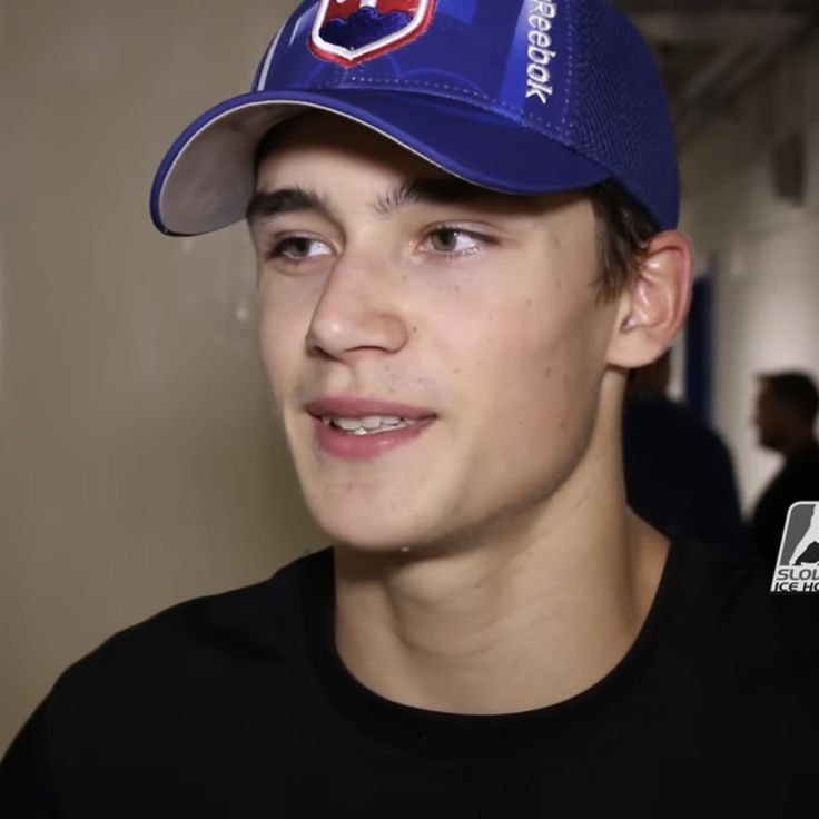 a young man wearing a blue hat and black shirt