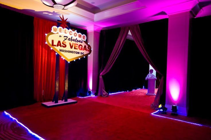 a red carpeted room with neon lights and drapes on the walls, along with a sign that reads welcome to las vegas