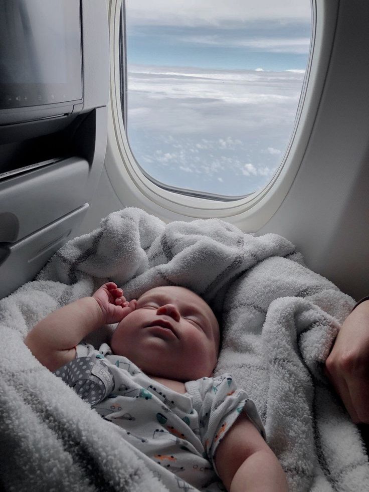 a baby laying on a blanket next to an airplane window