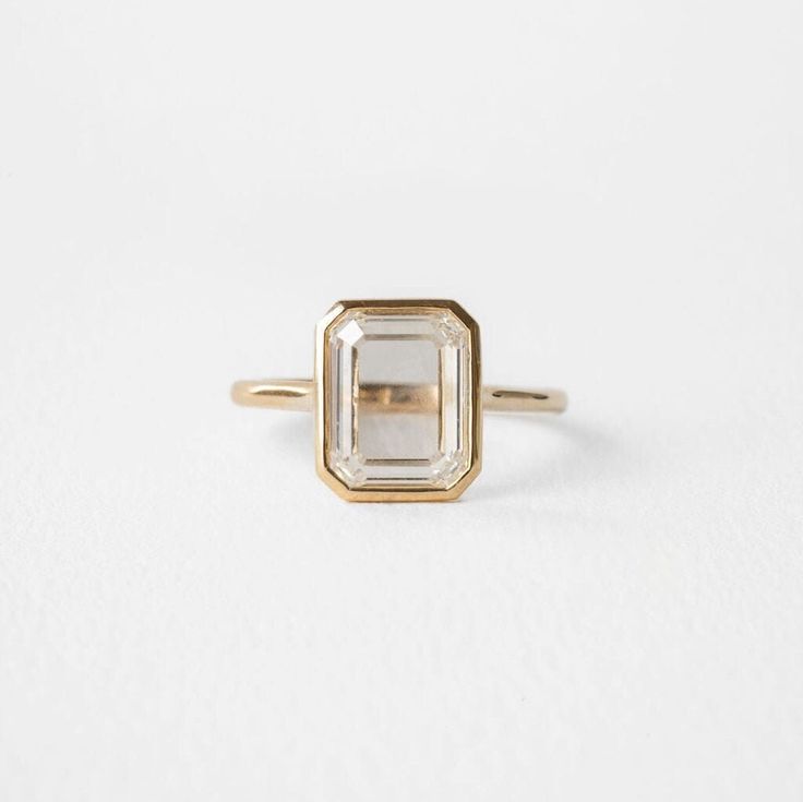 a gold and white diamond ring sitting on top of a white surface with no background