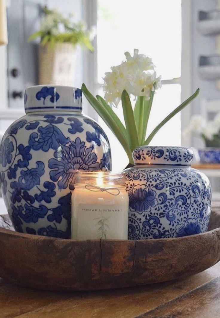 a blue and white vase sitting on top of a wooden table next to a candle