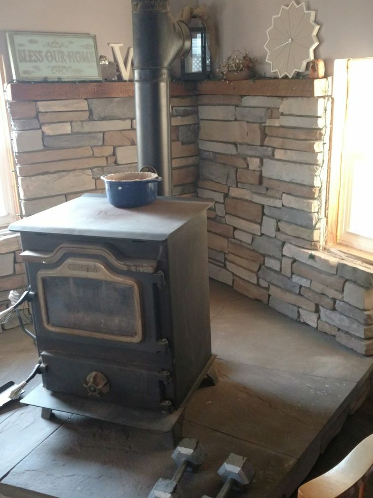 an old fashioned stove is in the middle of a room with stone walls and flooring