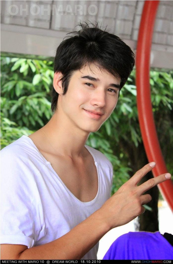 a young man is posing for the camera in front of a red pole and trees