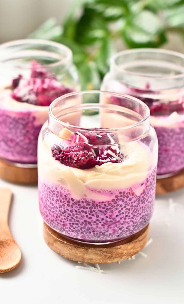 three desserts in small glass jars on a table