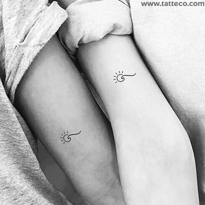 two people with matching tattoos on their arms, one is holding the other's arm