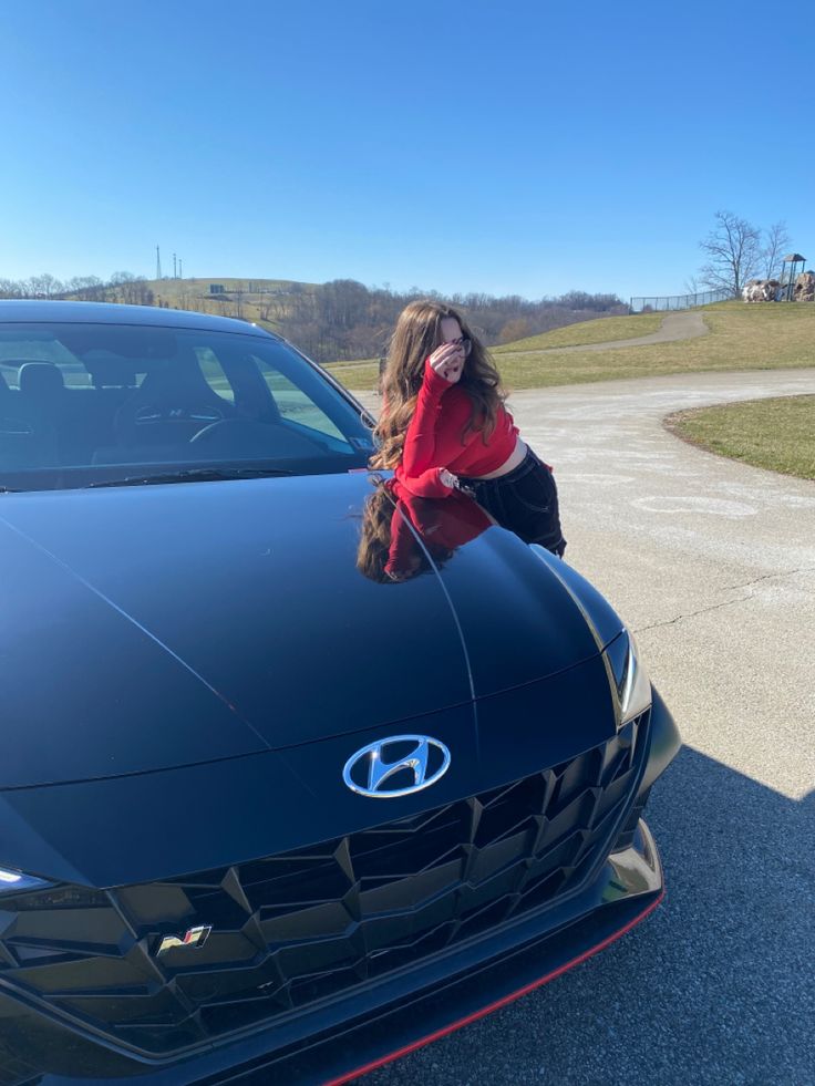 a woman leaning on the hood of a car