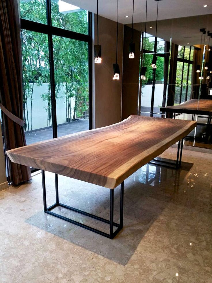 a large wooden table sitting in front of a glass window next to a wall mounted light fixture