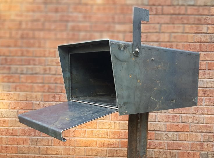 a metal mailbox sitting next to a brick wall