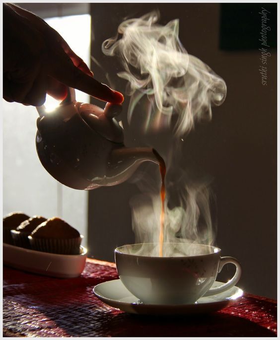 a person pouring coffee into a cup with steam rising from it on a saucer